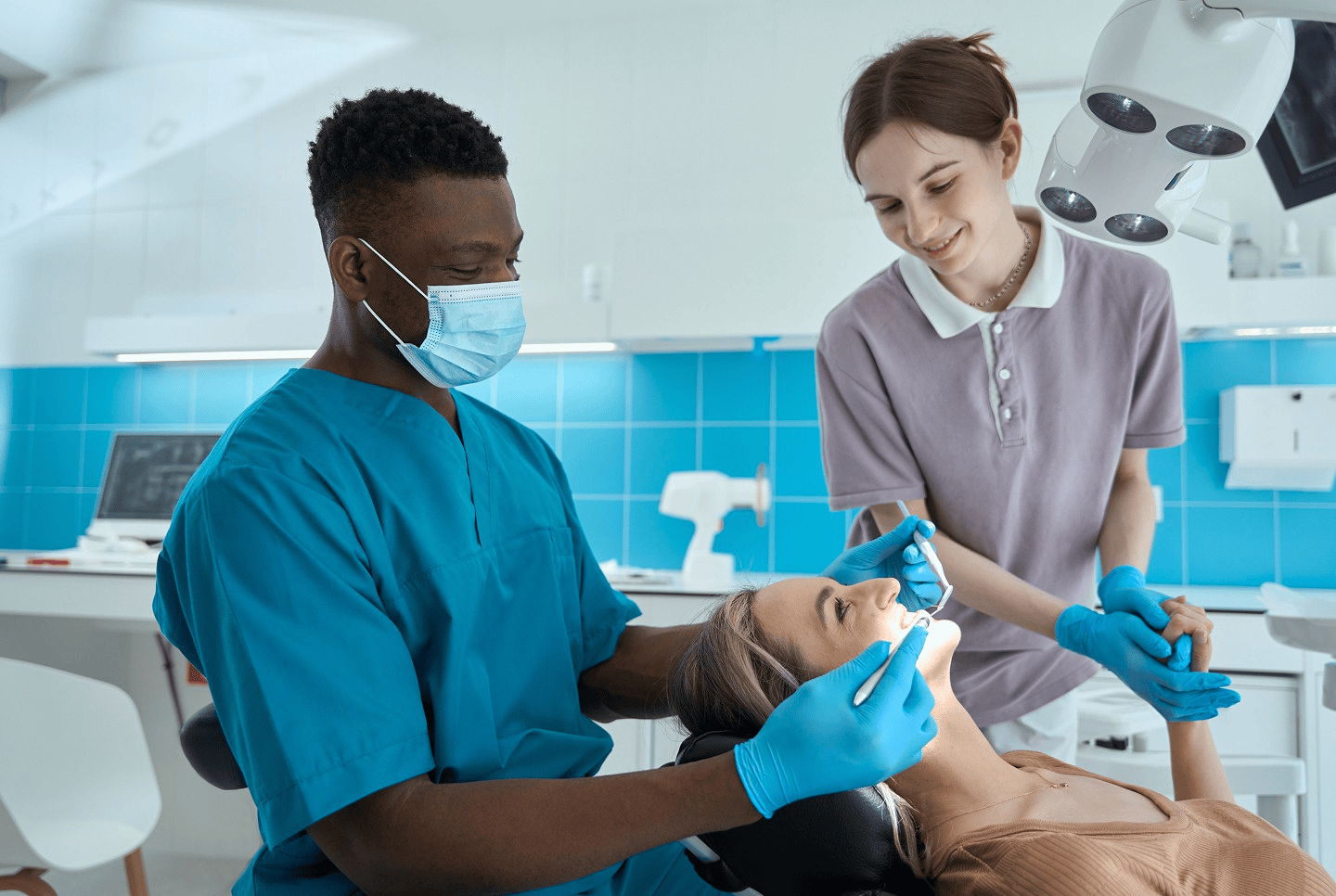 Dentist and assistant treating a smiling patient in a bright surgery
